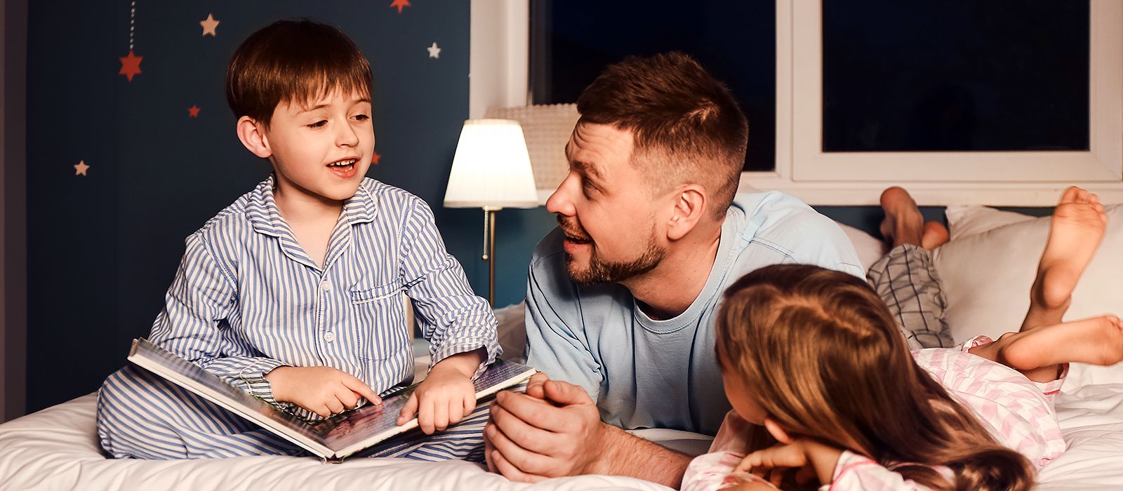 Vater mit Kindern bei der Gutenachtgeschichte